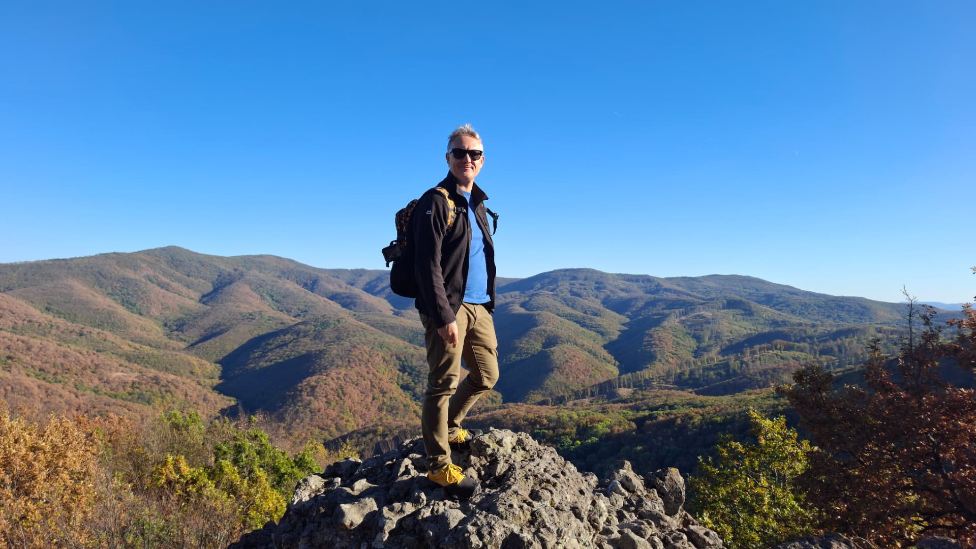 Philip Barnett on a rocky summit above autumn hills